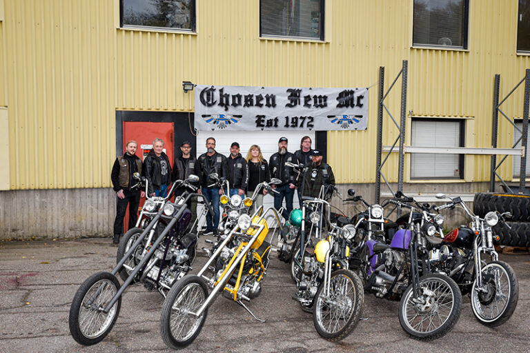 Några av medlemmarna i Chosen Few MC poserar framför klubblokalen tillsammans med några av sina motorcyklar.